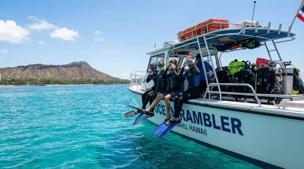 Tourists preparing to enter the water for a shark snorkeling tour on a boat in Hawaii