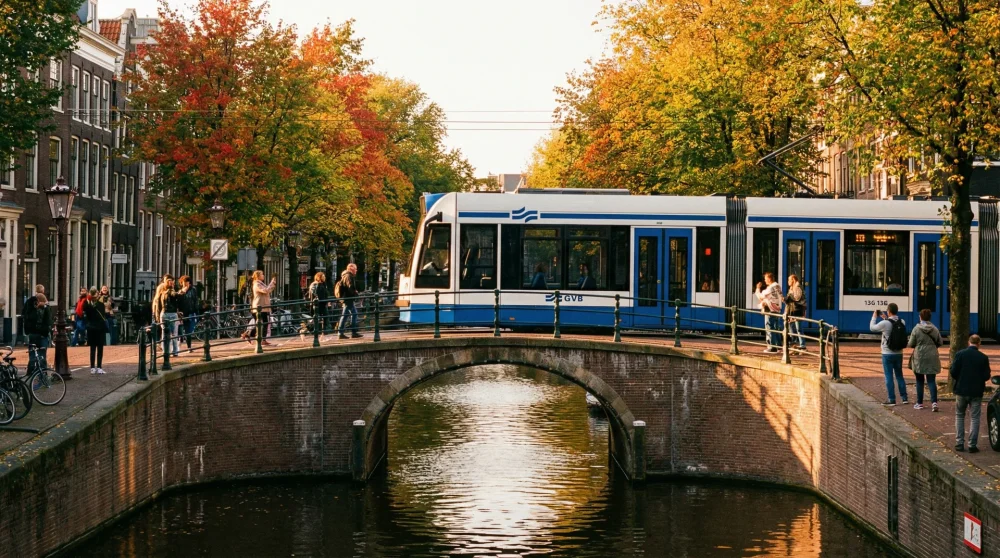 Blue and white GVB tram crossing a historic canal bridge in Amsterdam city center