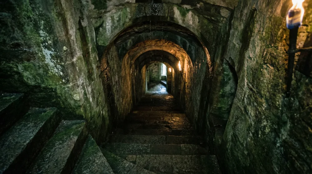 Steep stone steps and low arches inside the underground tunnels of Rheinfels Castle.