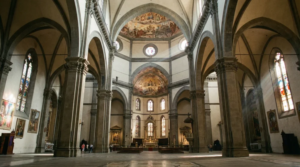The vast and austere interior nave of Florence Cathedral with high arches and stained glass