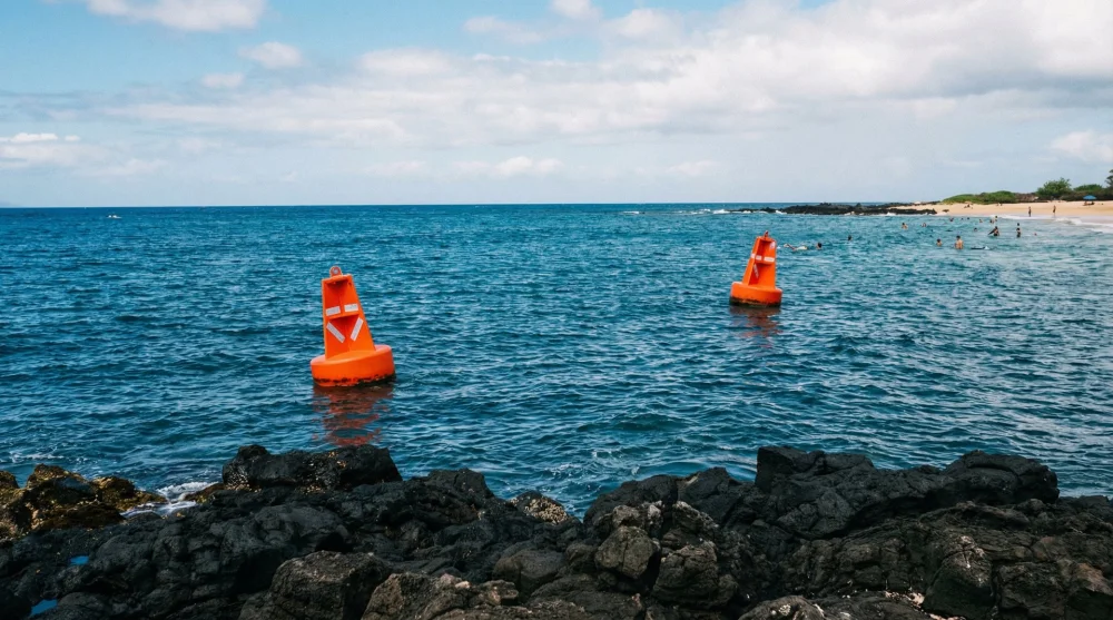 Two orange buoys marking the safe entry channel for snorkelers at Kahaluu Beach Park