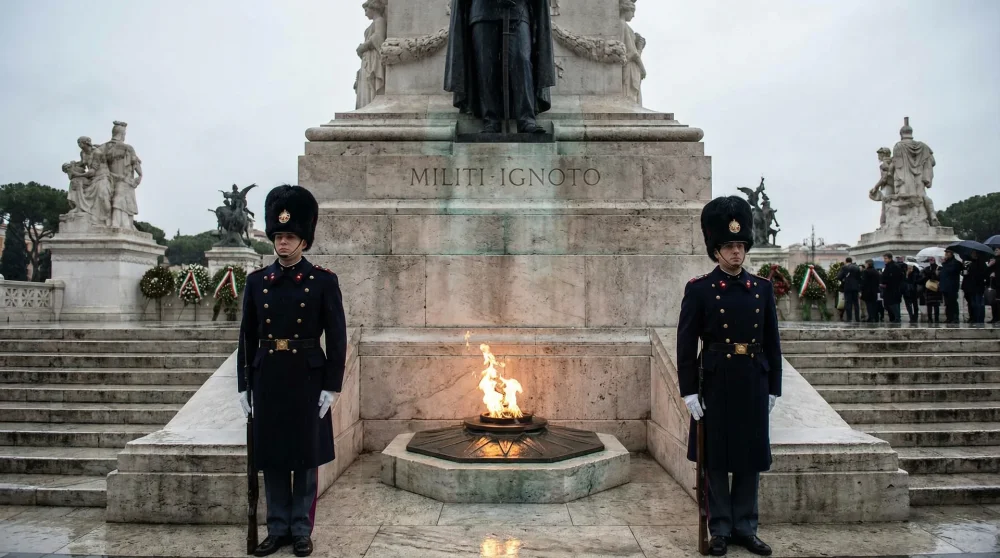 Italian military guards standing at attention next to the eternal flame at the Tomb of the Unknown Soldier