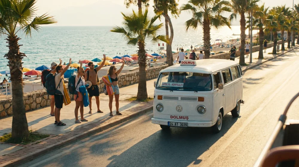 Ein typischer weißer Dolmus Minibus an der sonnigen Küstenstraße in Antalya, der von Touristen herbeigewinkt wird