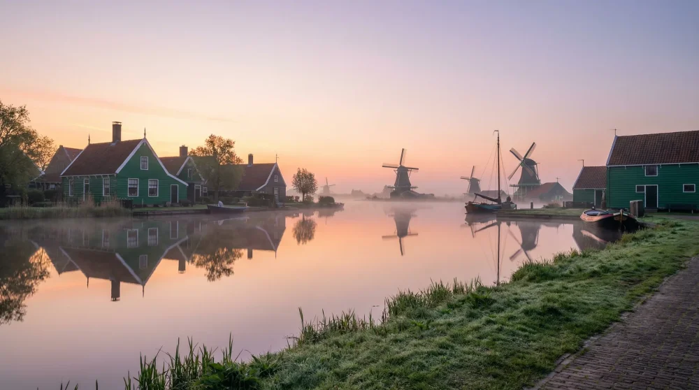 Panoramic view of Zaanse Schans green wooden houses and windmills reflected in the Zaan river at dawn