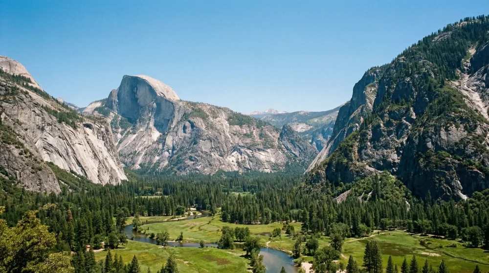 Glacier carved U-shaped valley of Kings Canyon with massive granite cliffs and green meadows in California.