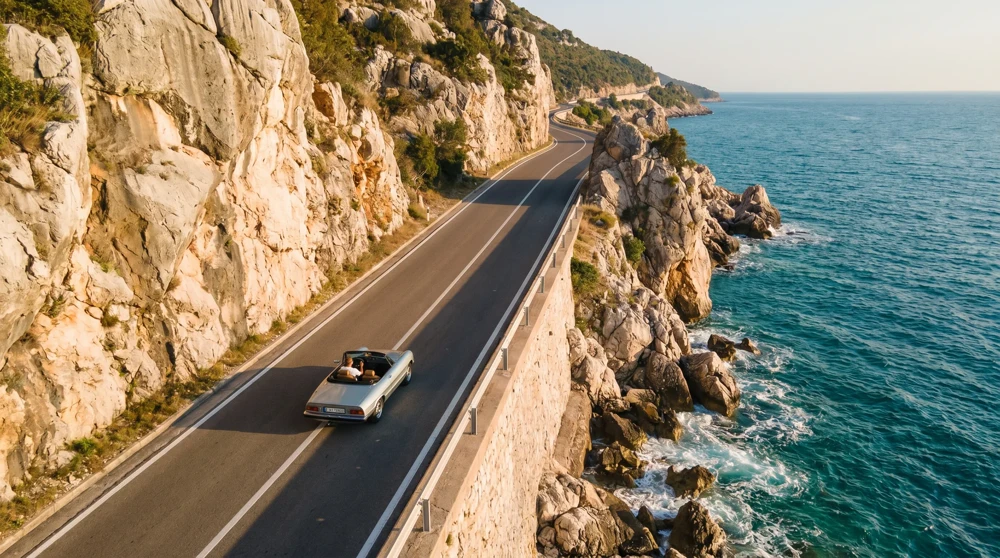 Wide aerial shot of the Adriatic highway winding along the blue sea and steep cliffs of Montenegro