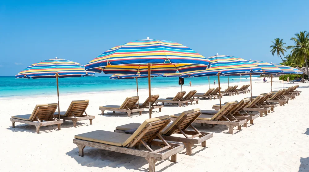 Reihen von Holzliegestühlen unter bunten Sonnenschirmen auf weißem Sand am Seven Mile Beach