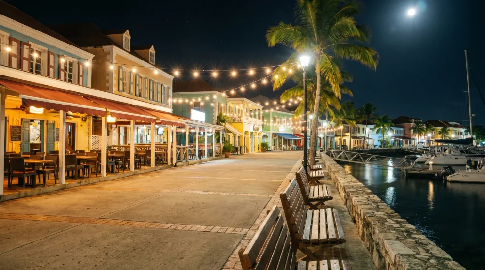 Pedestrian promenade at night with string lights and restaurant glow in Camana Bay Grand Cayman