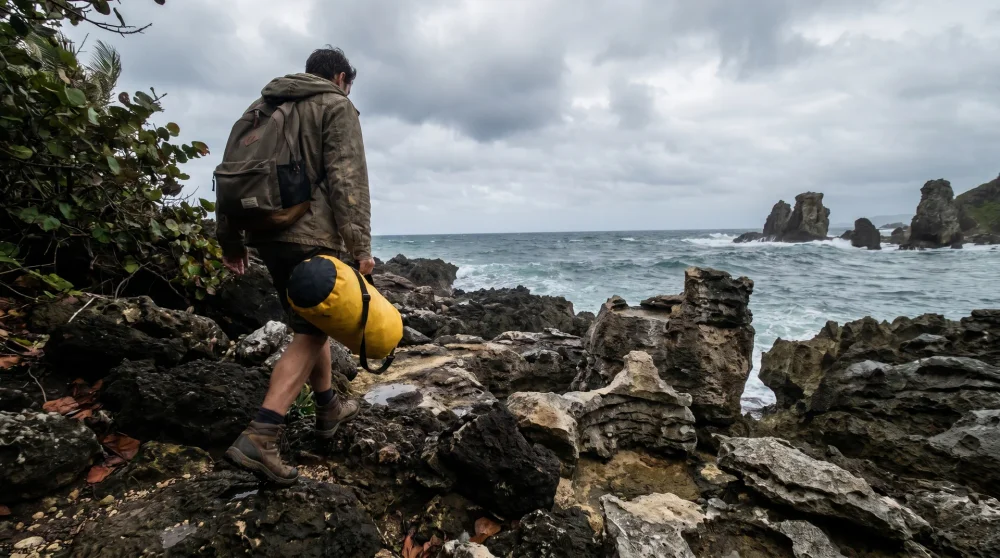 A diver approaching a shore entry point along the rugged coastline of Cayman Brac