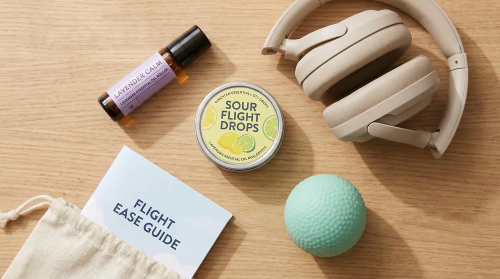 A collection of sensory grounding items including essential oils, headphones, and sour candy for flight anxiety management