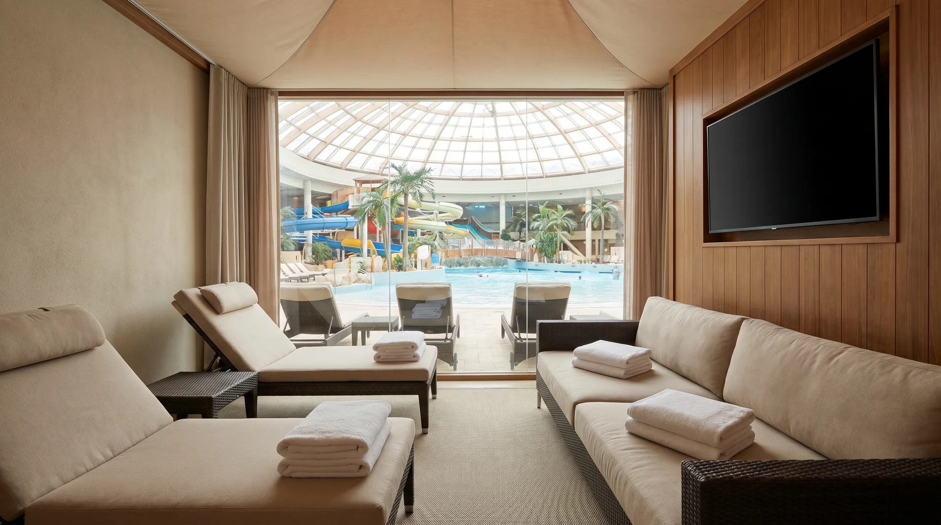 Private luxury cabana with comfortable furniture and amenities overlooking an indoor pool area