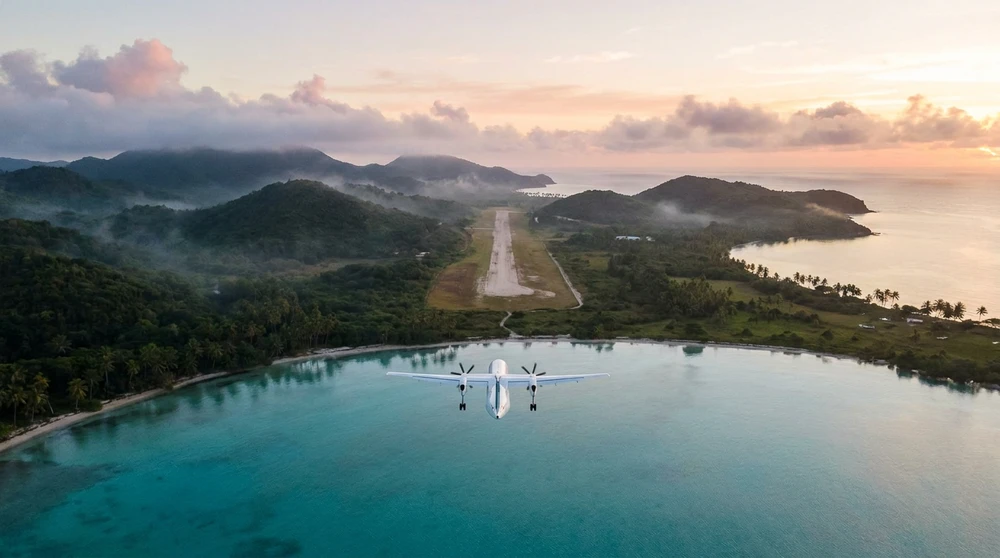 Luftaufnahme eines kleinen Flugzeugs, das sich bei Sonnenaufgang einer tropischen Inselpiste nähert