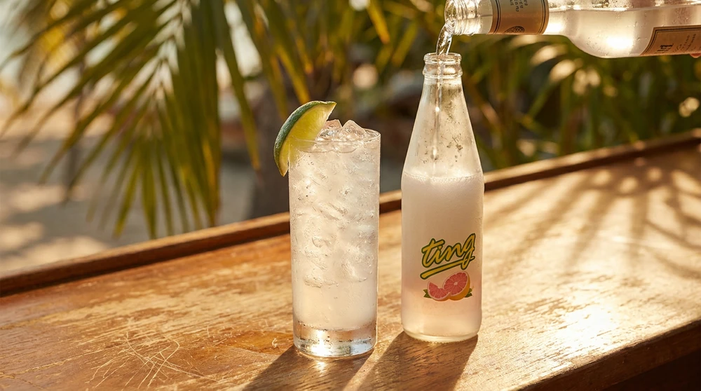 Local CSR white rum being poured into a chilled Ting grapefruit soda with lime wedge