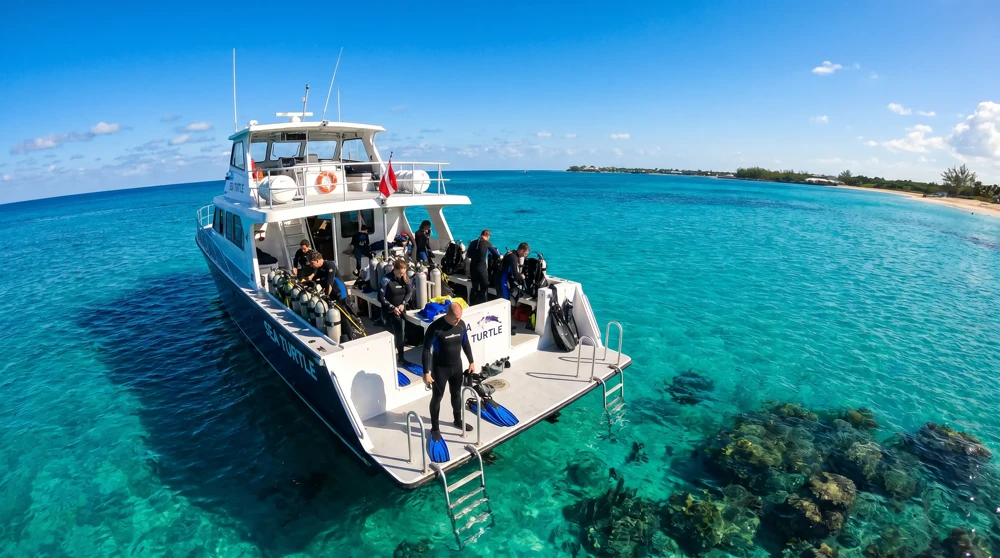 Tauchboot vor Anker auf dem leuchtend türkisfarbenen Meer vor Grand Cayman mit Tauchern an Deck