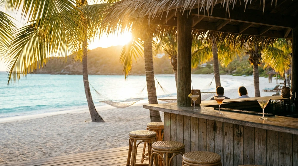 Goldene Stunde an einer hoelzernen Tiki-Bar an einem ruhigen Strand der südöstlichen Halbinsel von St. Kitts mit Palmen und türkisem Meer.