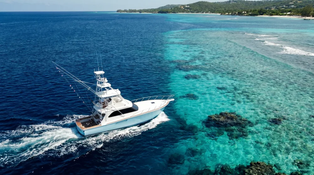 Sportfischer-Charterboot auf tiefblauem Wasser nahe Grand Cayman mit ausgebrachten Leinen
