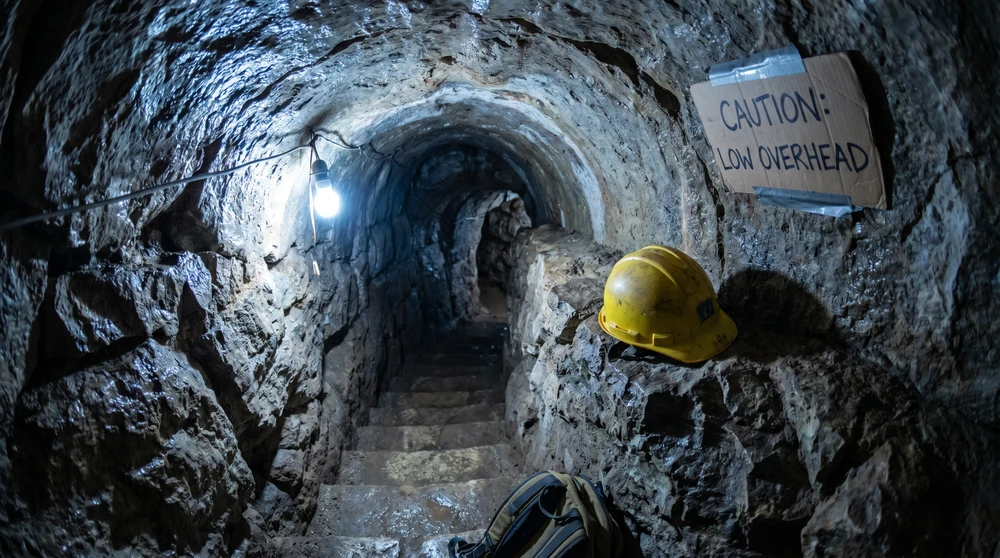A hard hat on a limestone ledge beside a narrow low-ceilinged tunnel passage