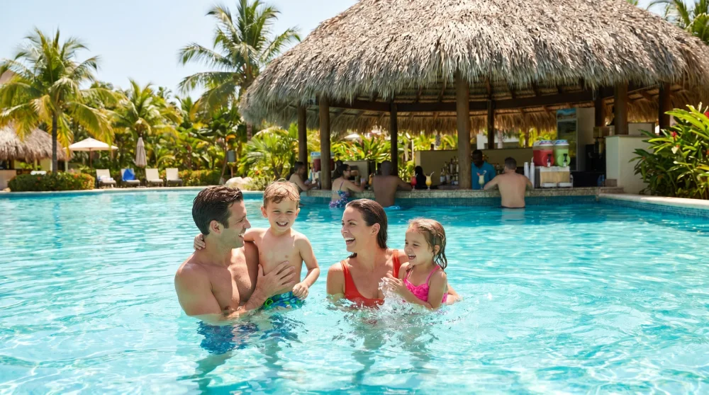 Family with children enjoying the pool at a Jamaica all-inclusive resort with swim-up bar in background