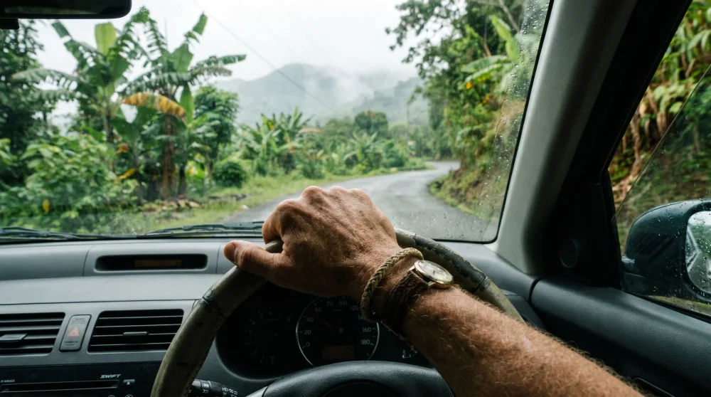 A driver navigating a narrow mountain road through lush Jamaican jungle