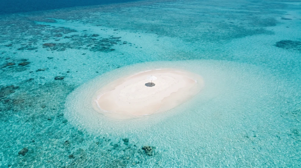 Winzige leere weiße Sandbank umgeben von türkisem Ozean bei einem Malediven-Ausflug