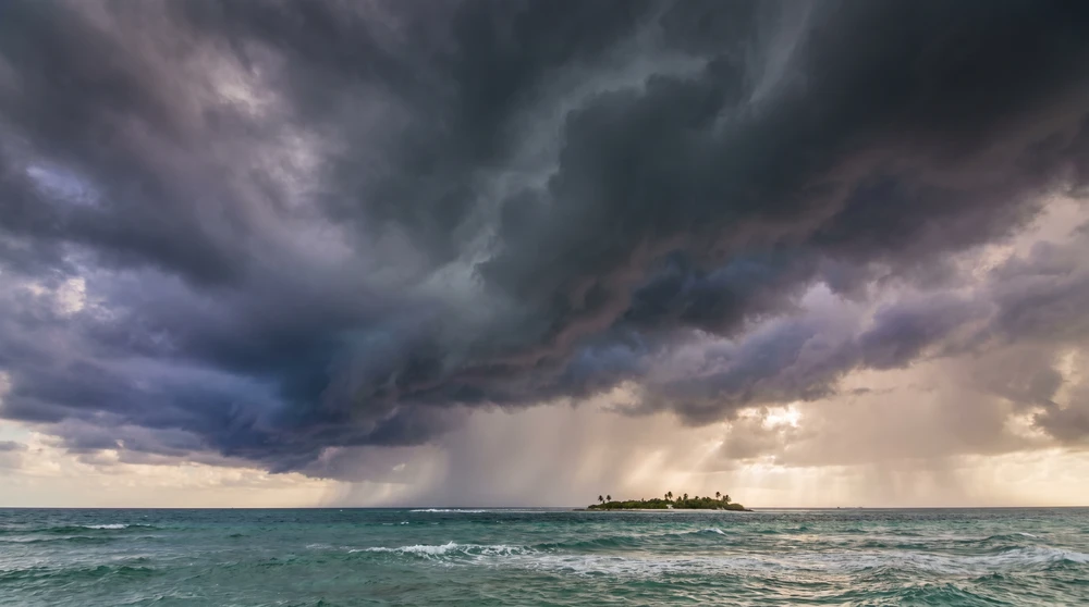 Monsoon storm clouds building over the ocean near a low Maldivian island