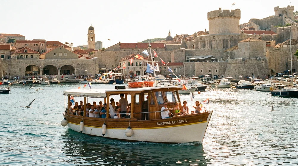 Passenger ferry crossing a sunny Malta harbour below fortified town walls