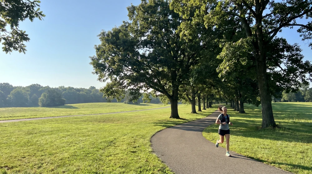 Solo runner on a flat paved loop through green parkland in Malta