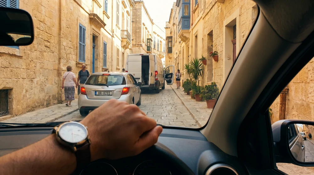 Rental car stuck behind a delivery van on a narrow Maltese street, illustrating how short distances take longer than expected