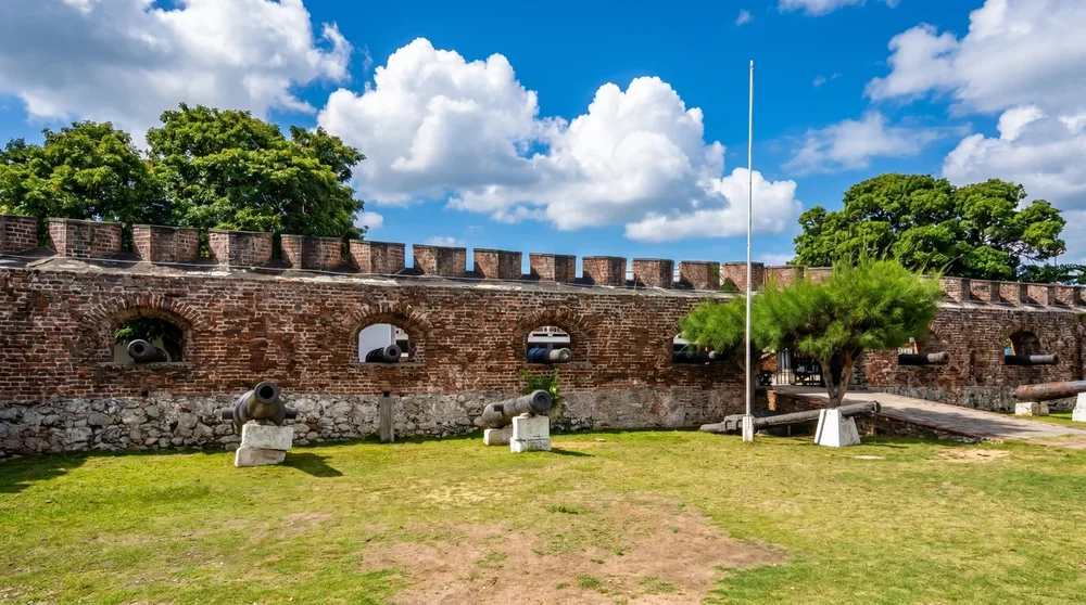 Weathered stone fort walls with antique iron cannons overlooking the harbour at Port Royal Jamaica