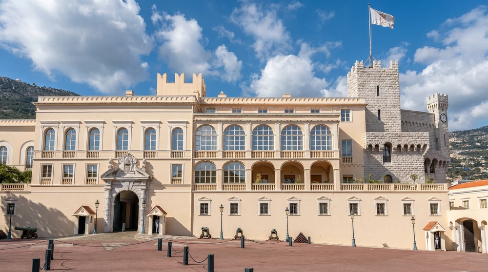 The ochre-painted facade of the Prince's Palace of Monaco at Palace Square with tourists gathered outside