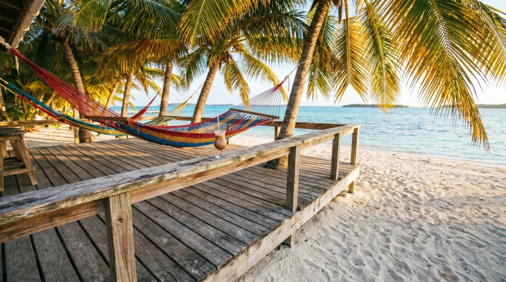 Holzterrasse des Rum Point Club mit Hängematten und Kokospalmen auf Grand Cayman