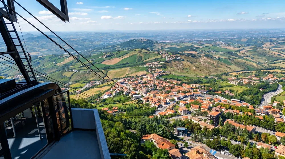 Blick aus der Funivia-Kabine in San Marino auf die Dächer von Borgo Maggiore und die Adriaküste in der Ferne