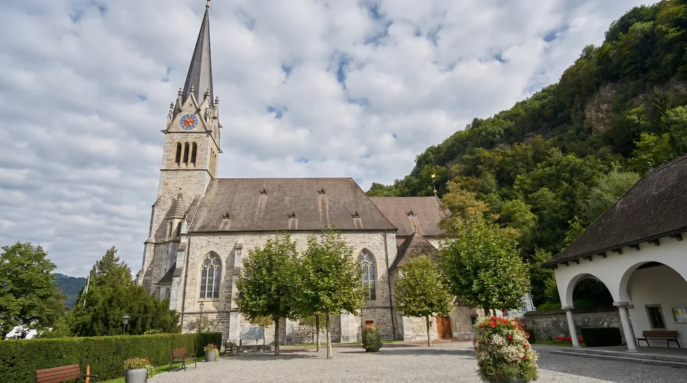 Kathedrale St. Florin mit neugotischem Turm und baumgesäumtem Vorhof in Vaduz, Liechtenstein