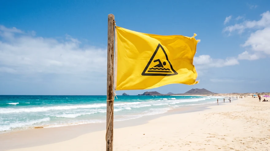 Yellow warning flag on a Cabo Verde beach with white sand and turquoise Atlantic water in the background