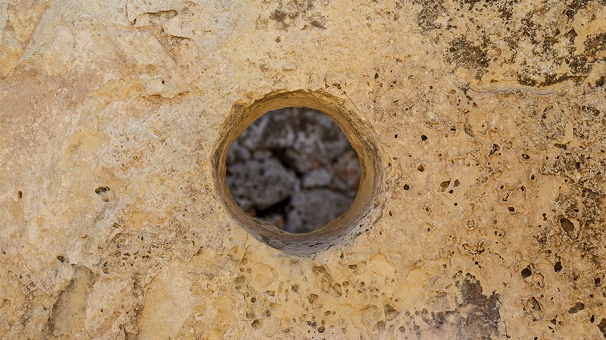 Close-up of a precisely bored circular hole worked through a weathered limestone block at the Ggantija temples