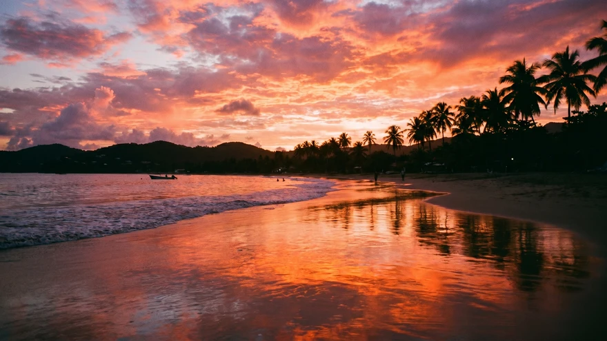Sunset at Grand Anse Beach Grenada with orange sky and wet sand reflections