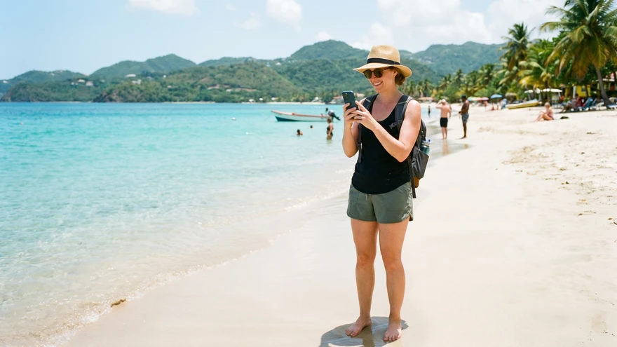 Traveler checking smartphone connectivity on Grand Anse Beach Grenada