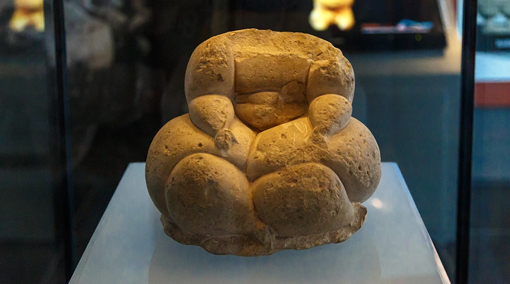 Eine prähistorische rundliche Steinfigur, eine maltesische Fat-Lady-Statuette, in einer beleuchteten Vitrine ausgestellt