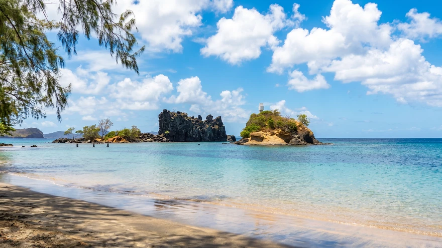 Indian Bay beach St. Vincent with a black volcanic rock and cross-topped islet in clear turquoise water