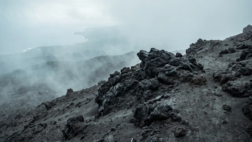 Close-up of black volcanic rock and gray ash terrain on upper La Soufriere trail post 2021 eruption St Vincent