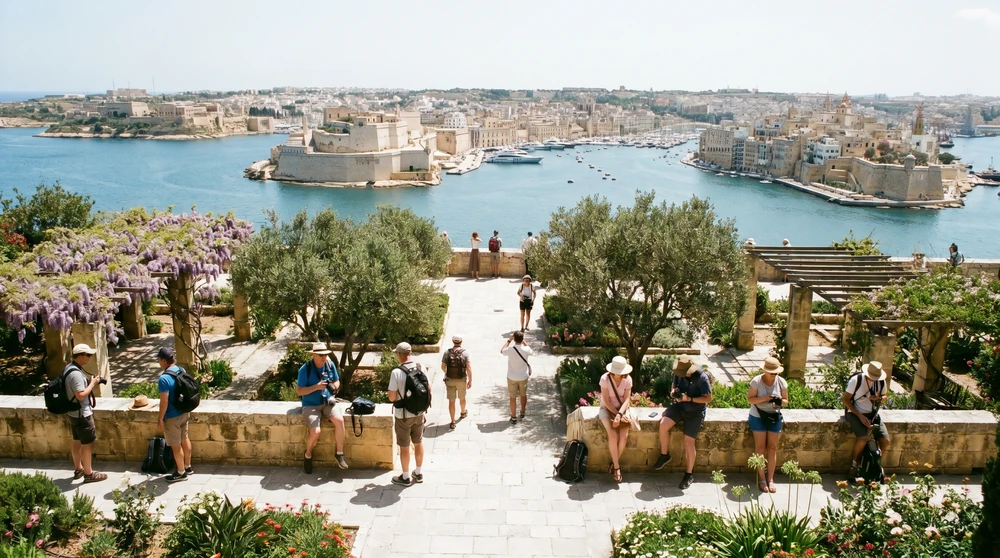 Travelers on a stone garden terrace overlooking a grand natural harbour with fortifications across the water