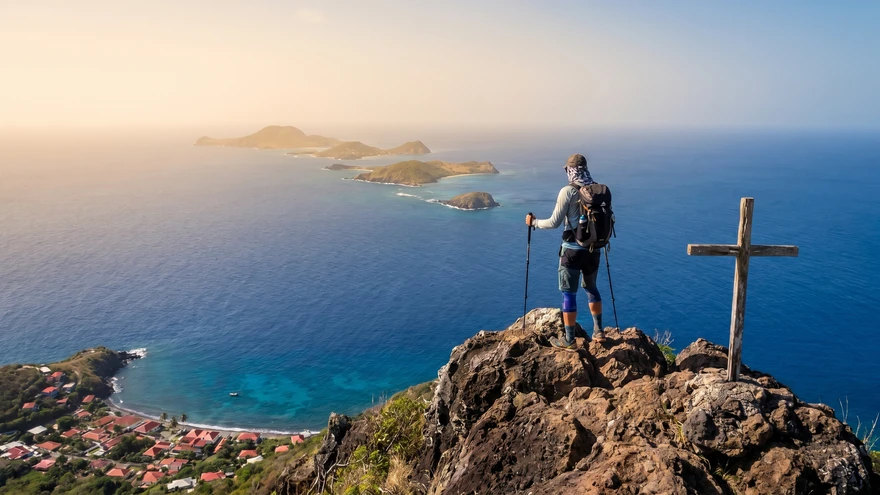 lone hiker stands at the rocky summit of the Piton on Petite