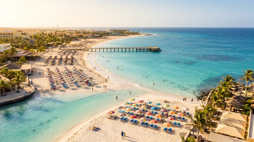 Santa Maria beach in Sal, Cabo Verde, showing the gently curved bay with turquoise water and wooden pier