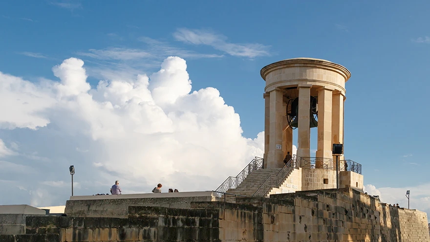 The neoclassical domed Siege Bell War Memorial on the Grand Harbour bastions in Valletta under a bright sky