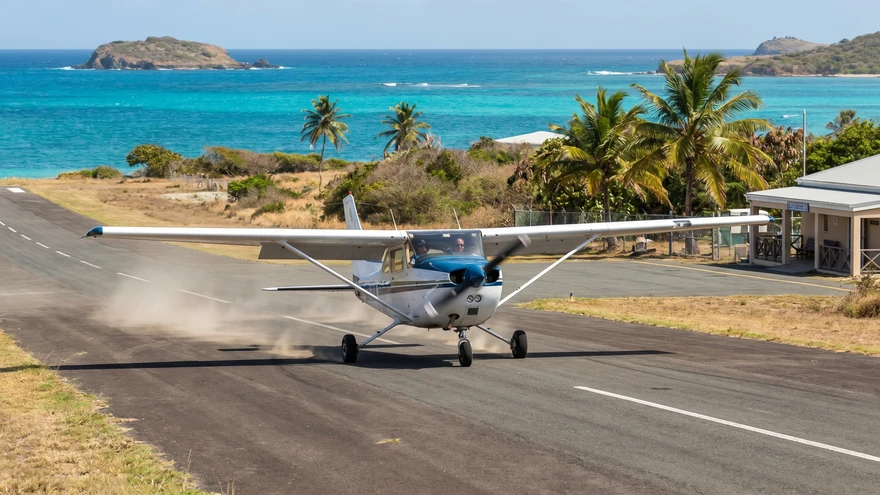 Small aircraft landing at Lauriston Airport Carriacou with sea view