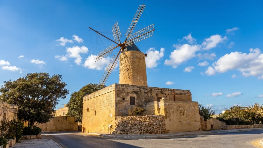 The restored Ta' Kola Windmill with its six wooden sails above a honey-coloured stone tower in Xaghra, Gozo