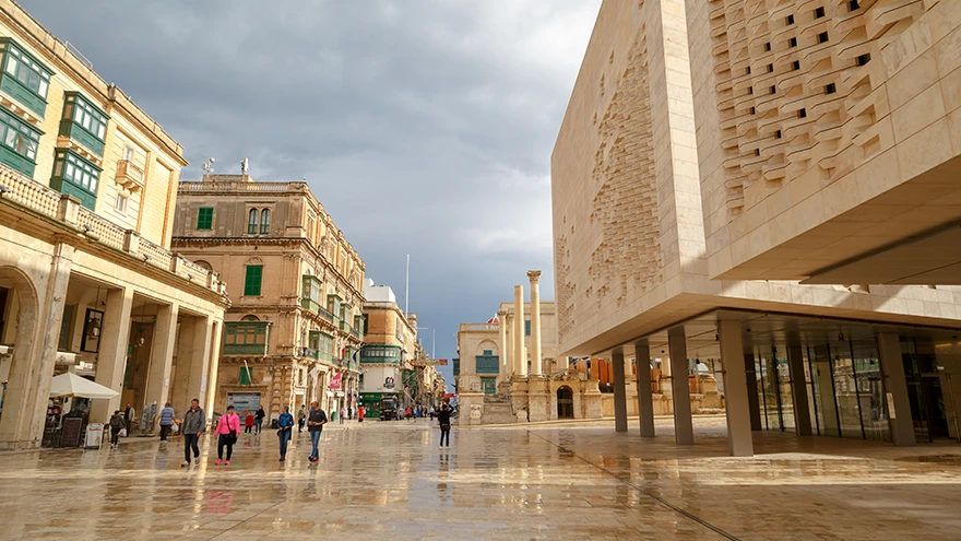 The wide stone plaza of Republic Street by City Gate with the modern Parliament building, wet and reflective after rain in Valletta