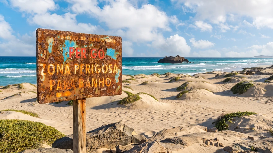 Rusted danger warning sign on the sand at Praia da Atalanta, Boa Vista