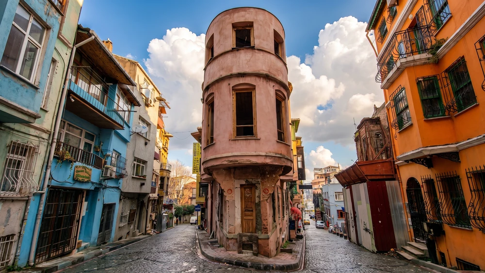 Sancaktar Yokusu in Balat with a distinctive round corner building, steep cobblestones, and colorful residential buildings.