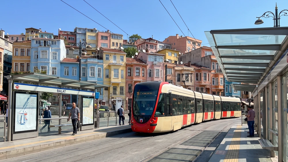 The Balat T5 tram stop with the colorful houses of Kiremit Street visible on the hill above
